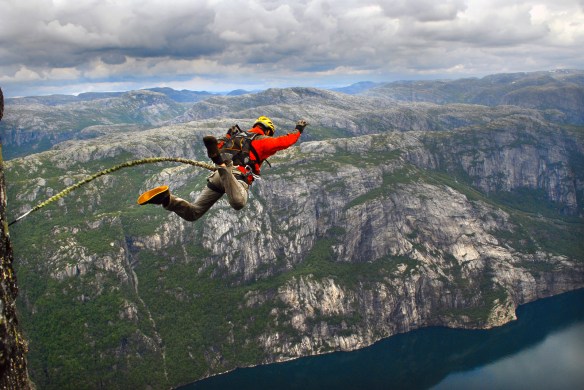 Man jumping off a cliff with a rope.